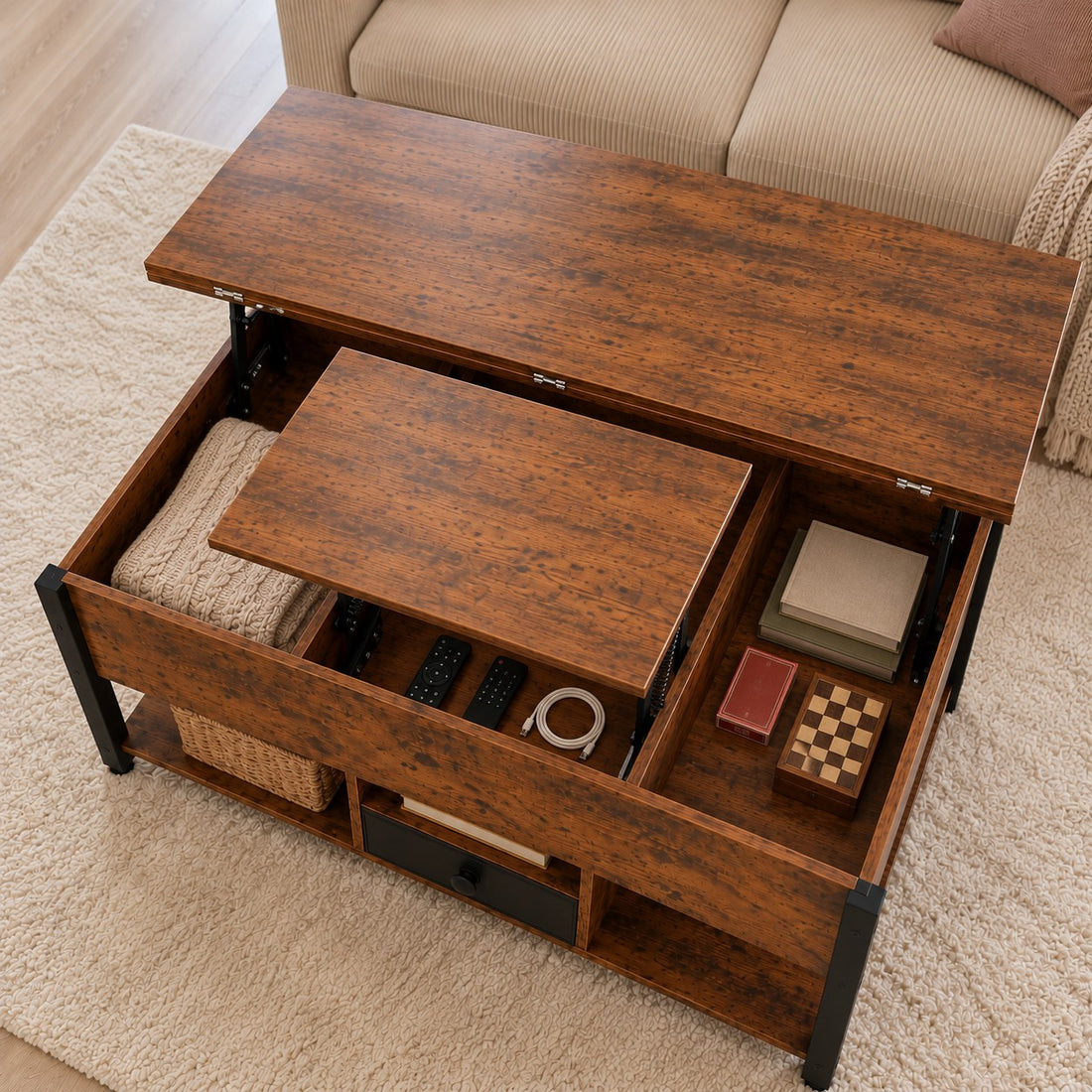 Coffre ouvert de la table basse relevable Estrora, avec un plaid, des télécommandes et des jeux rangés
